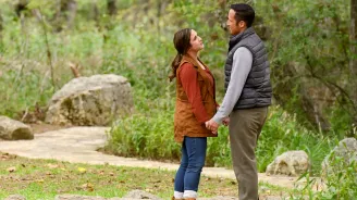 Couple standing and holding hands on a path in the forest.