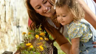 Mother and daughter smelling flowers. 