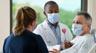Man in an AdventHealth emergency room with a doctor and nurse.