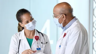 Two doctors talking while wearing masks.