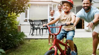 Family teaching son to ride bike in yard