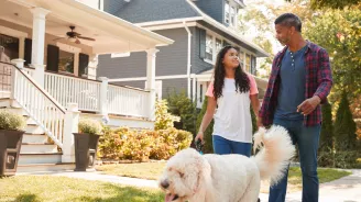 Father and daughter walking dog through their neighborhood