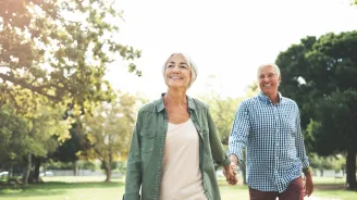Elderly couple holding hands and walking in a park