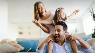 Man laughing carrying his daughter on his shoulders