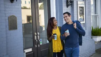 Hispanic Couple walking outdoors with coffee