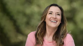 A smiling woman wearing a pink shirt.