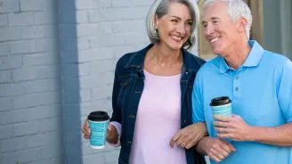 Older couple walking with coffee