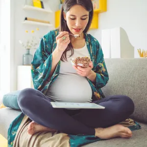 A pregnant woman eating breakfast. 