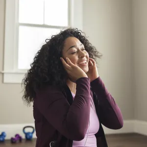 A young African American woman enjoys her music through her earbuds. 