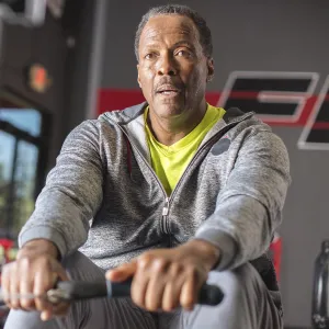 An African American man exercises on a rowing machine at the gym.