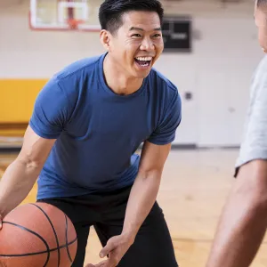 Two men play basketball together at the gym.
