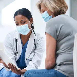 Doctor speaks to her middle aged female patient while going over some notes.