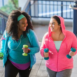 A Pair of Ladies, in Brightly Colored Clothing, Go Jogging in the City with Hand Weights.