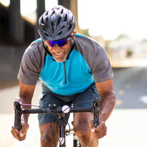 A Middle Aged Man Rides a Bicycle on a Road while Dressed in Typical Cyclist Attire.