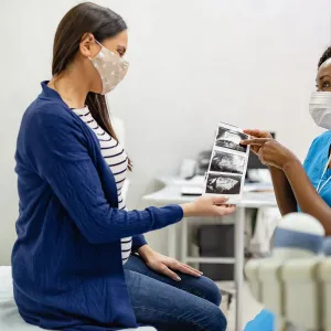 A Woman Looks Over The Sonogram of Her Baby with Her Physician.