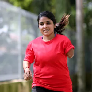 A Teenage Girl with One Lower Arm Runs in a Park.