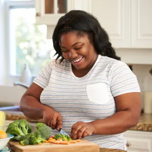 A Woman Chops Vegetables in a Modern Kitchen with a Smile on Her Face.