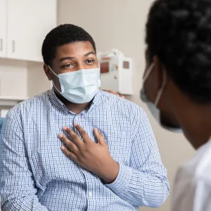 A Man Speaks to His Doctor in a Patient Room While Being Comforted with a Family Member.