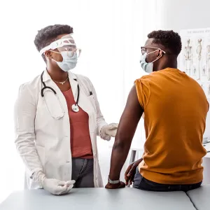 A Doctor Examines Her Patient in an Exam Room while Wearing PPE