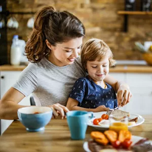 A Mother Feeds a Picky Eater Child at The Kitchen Table.