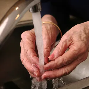 A Close Up of a Senior Woman Washing Her Hands in the Kitchen Sink