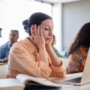 A Woman Holds Her Head In Her Hands as She Tries to Concentrate in a Class