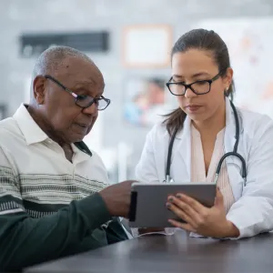 A Provider Goes Over a Patient's Chart with Him on a Tablet.