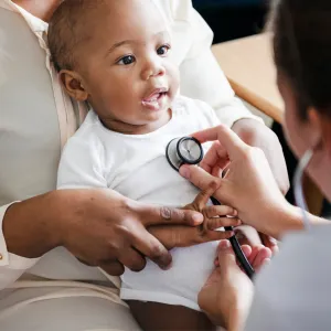 A Physician Checks a Smiling Baby's Breathing with a Stethoscope