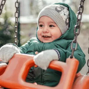 A Small Child in a Swing on a Playground.