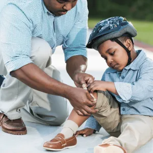 A Boy and His Father Tend to His Knee After Taking a Spill on a Bicycle
