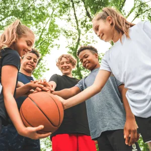 Five Teens Huddle Around a Basketball in a Park