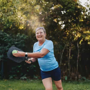 A Senior Lady Plays Pickle Ball in a Park
