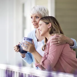 Two women converse on the front porch while drinking coffee.