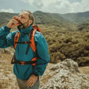 A Man Uses a Inhaler on a Hike Through Rough Terrain