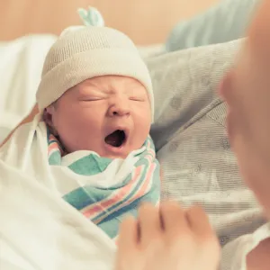 Newborn baby yawning in it's mother's arms