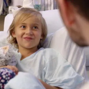 Charlotte sits with her doctor in her hospital room.