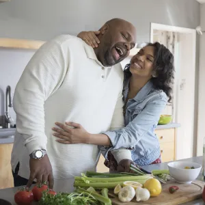 A couple shares a sweet moment as they prepare vegetables in their kitchen