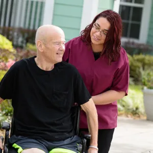 Elderly man in a wheelchair outside with a nurse.