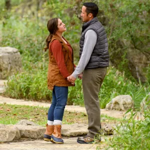 Couple standing and holding hands on a path in the forest.