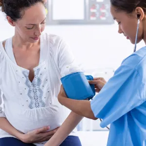 Pregnant woman gets her blood pressure checked at the doctor.