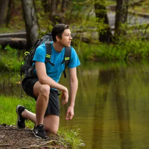 Taking a rest near a lake while hiking through the woods.