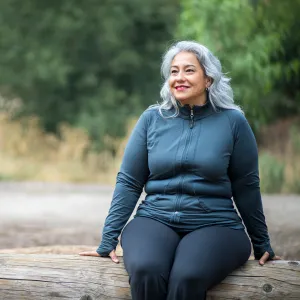 A Hispanic Woman Sits on a Log, Taking a Break From a Hike