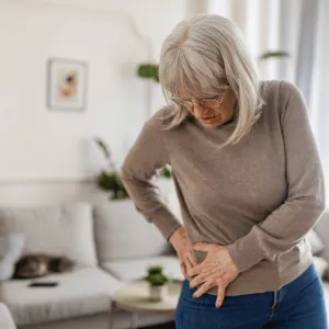 An older woman holds her hip in pain.