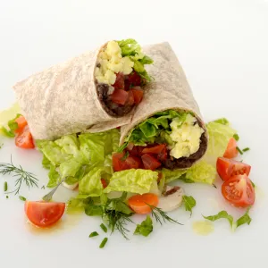 Breakfast burrito halved and stacked with tomato and green garnishes