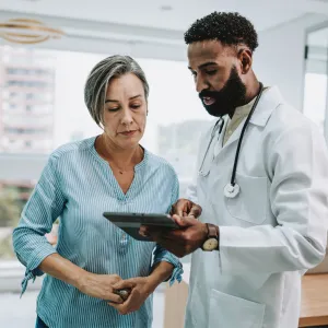 An older woman reviews test results on a tablet with her physician.