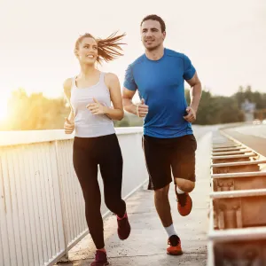 A Young Couple jogging at sunset by a road