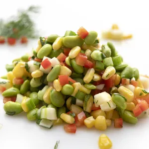 Mound of edamame corn salad on white surface