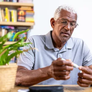 An older man using a blood sugar measuring device