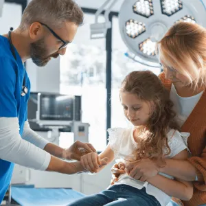 Doctor evaluating at a young girl's arm.