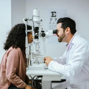 Doctor looking at a young woman's eyes during optical exam.